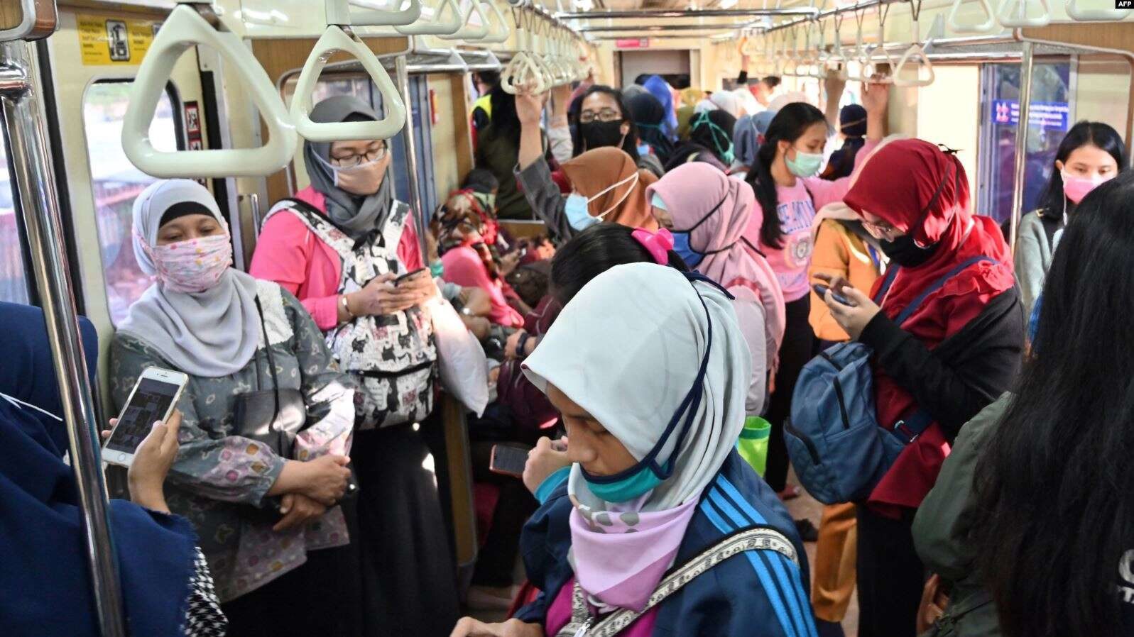 Para penumpang perempuan mengenakan masker di tengah wabah virus corona Covid 19 di gerbong kereta commuter di Jakarta