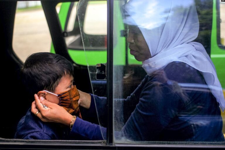 Rencana Denda Warga yang Tidak Pakai Masker Dinilai Tidak Efektif 6 Seorang ibu memasang masker wajah untuk anaknya di dalam angkutan umum di Bogor Jawa Barat