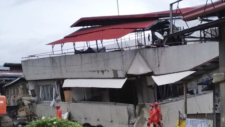 Gempa Kuat Guncang Filipina Tengah, Banyak Warga Panik Berlarian ke luar Rumah 2 Tim penyelamat berjalan di samping gedung South Green Marketing tiga lantai yang runtuh di Padada Provinsi Davao del Sur Filipina selatan